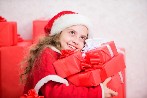 Le Père Noël apporte son cadeau. Les rêves deviennent réalité. Concept de bonheur d'hiver. Découvrez les cadeaux de Noël. Déballage du cadeau de Noël. Kid excité par le cadeau de Noël. Miracle de l'hiver. Fille fête Noël.