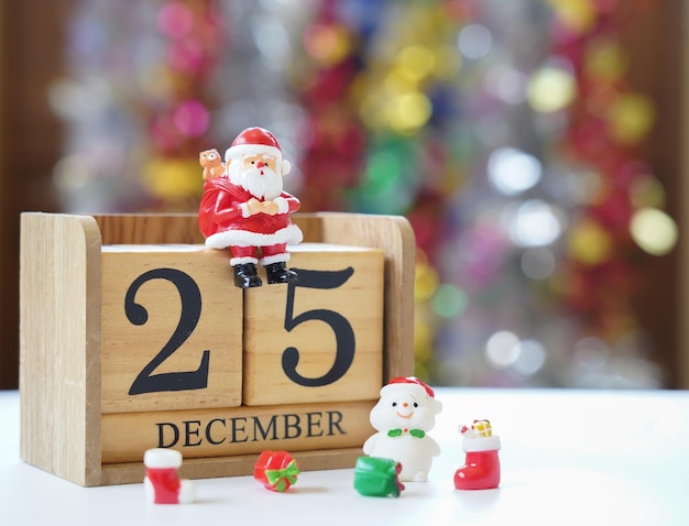 Père Noël assis sur un bloc de bois date du 25 décembre avec bonhomme de neige et cadeaux en attente d'un festival amusant Noël et bonne année pour faire une carte de voeux