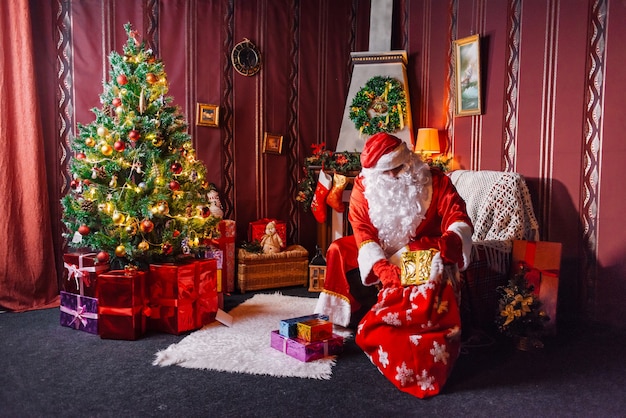 Père Noël assis à côté d'un arbre de Noël