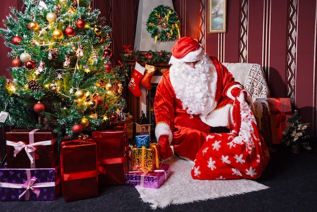 Père Noël assis à côté d'un arbre de Noël