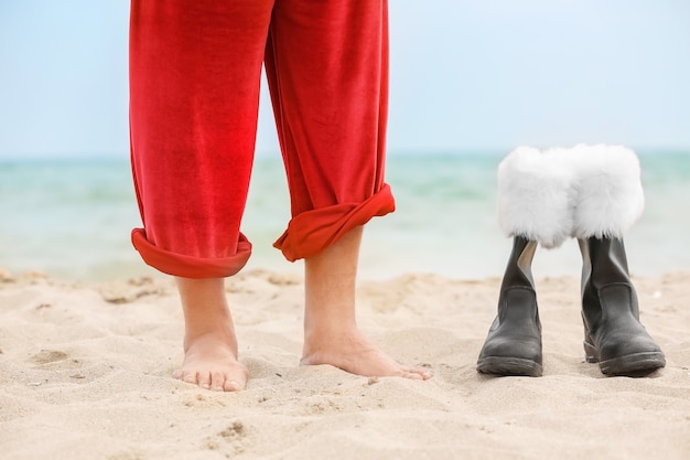 Père Noël aux pieds nus et bottes sur la plage