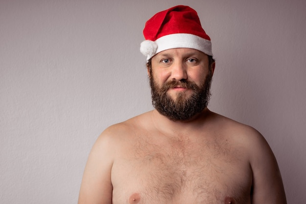 Père Noël barbu à moitié nu avec une longue barbe en chapeau de Noël ou du nouvel an de Noël