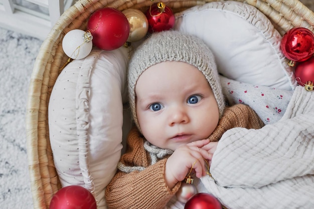 Père Noël bel enfant se trouve dans le berceau près de l'arbre de Noël Joyeux Noël et bonne année