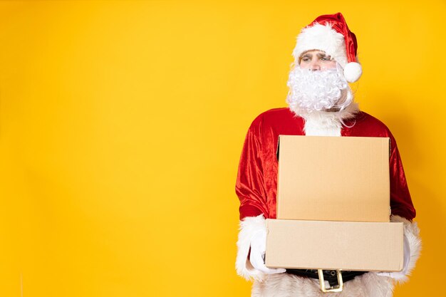 Photo le père noël avec des boîtes sur un fond jaune