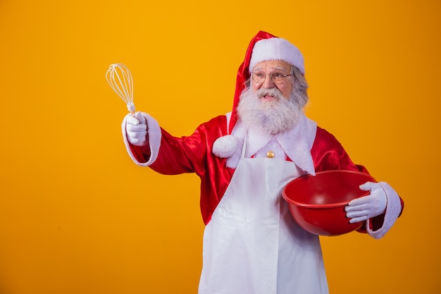 Père Noël avec un bol battant le gâteau sur fond jaune