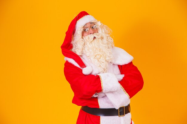 Père Noël avec les bras croisés sur fond jaune.