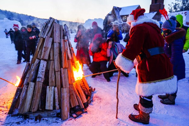 Le Père Noël brûlant du bois à Noël pendant l'hiver au crépuscule