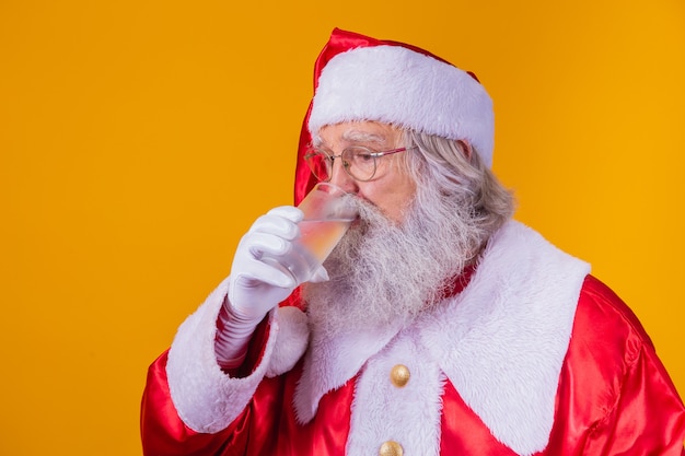 Père Noël buvant un verre d'eau sur fond jaune avec un espace pour le texte. Concept de santé et d'hydratation