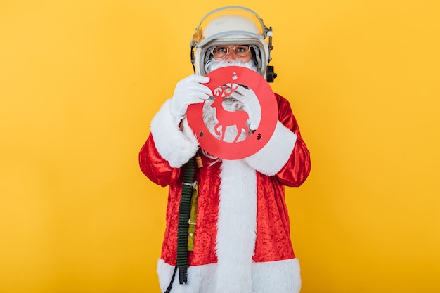 Père Noël en casque d'astronaute avec un panneau de signalisation de rennes sur jaune