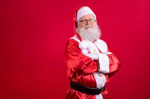 Le père Noël a croisé les bras sur fond rouge. Genre père Noël barbu avec les bras croisés sur fond rouge. Prise de vue en studio du père Noël réaliste.