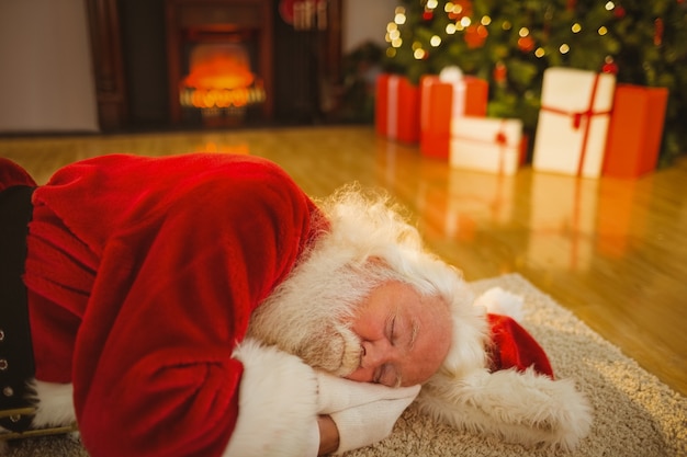 Père Noël dormant sur le tapis