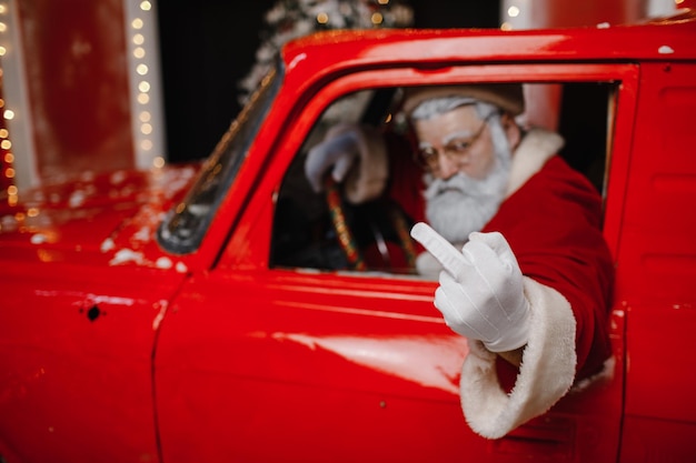 Le Père Noël élégant et agacé en colère au volant d'une voiture rouge Le Père Noël se prépare pour Noël