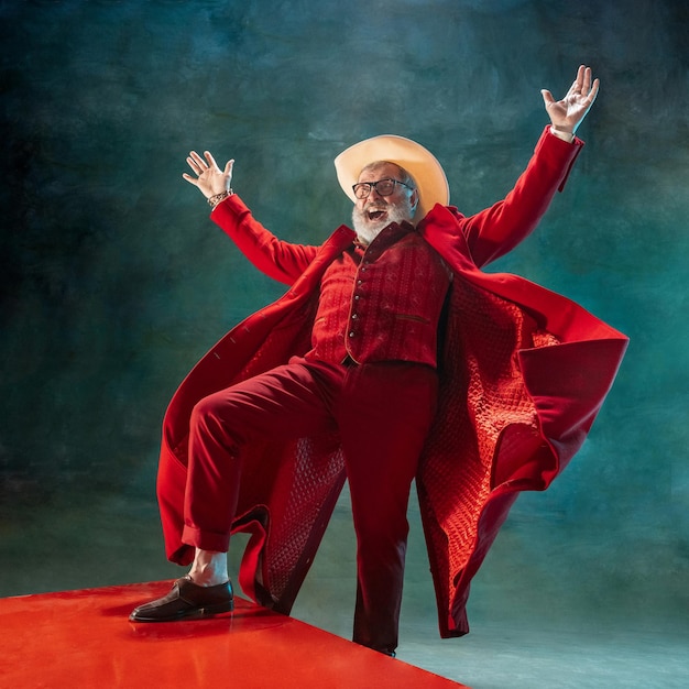 Photo père noël élégant et moderne en costume à la mode rouge et chapeau de cowboy sur fond sombre