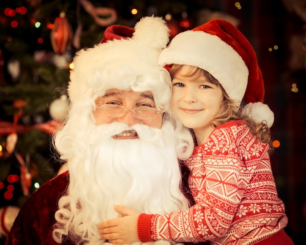 Père Noël et enfant à la maison contre l'arbre de Noël. Concept de vacances en famille.