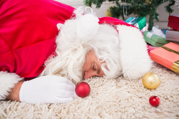 Père Noël épuisé reposant sur le tapis