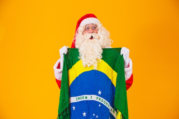 Le Père Noël est fan du Brésil. Père Noël supporter de l'équipe brésilienne. Championnat sportif. Père Noël tenant le drapeau brésilien. Match de football.