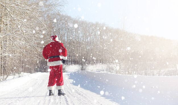 Le Père Noël est livré avec des cadeaux de l'extérieur. Le Père Noël en costume rouge avec une barbe et portant des lunettes marche le long de la route de Noël. Le Père Noël apporte des cadeaux aux enfants.