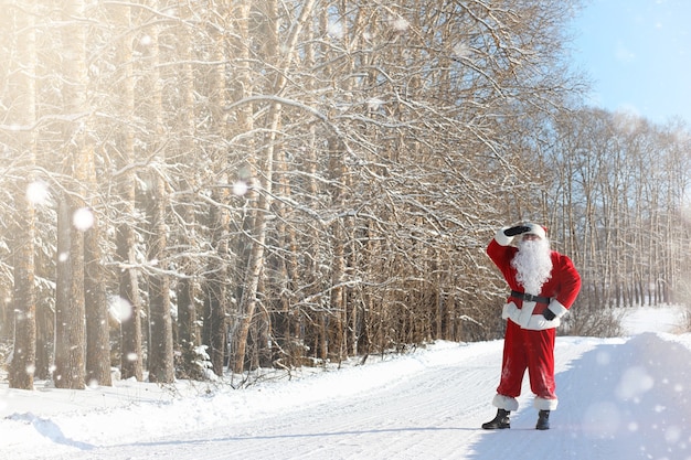 Le Père Noël est livré avec des cadeaux de l'extérieur. Le Père Noël en costume rouge avec une barbe et portant des lunettes marche le long de la route de Noël. Le Père Noël apporte des cadeaux aux enfants.