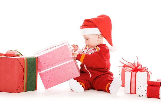 Père Noël helper bébé avec des cadeaux de Noël sur un mur blanc