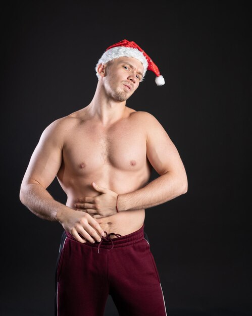 Père Noël Jeune beau irrésistible sur fond noir Dans un bonnet rouge le soir du Nouvel An