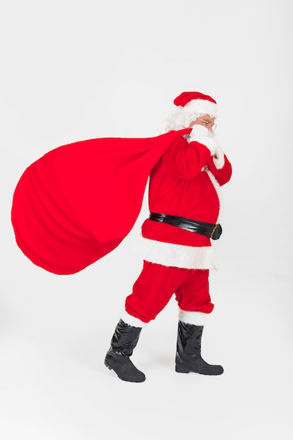 Photo père noël marchant avec un sac de cadeaux