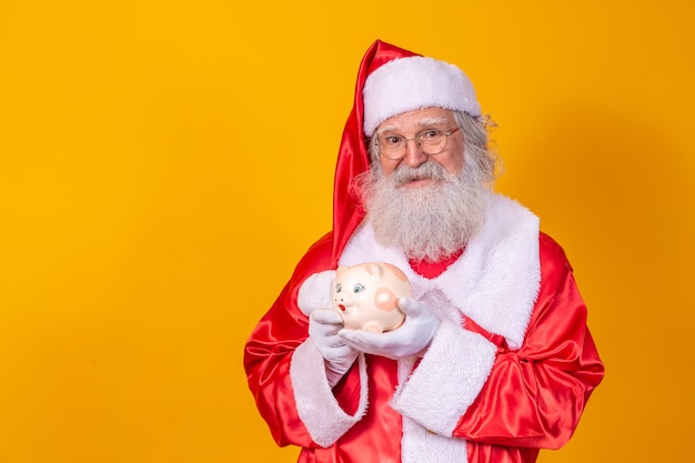 Le Père Noël met la pièce dans une tirelire en céramique. Concept d'épargne pour la fin de l'année. Dépenses à Noël. Dépensé en cadeaux de Noël.