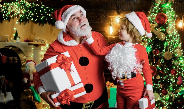 Père noël avec mignon enfant garçon à la maison le soir de noël vacances en famille et concept de l'enfance