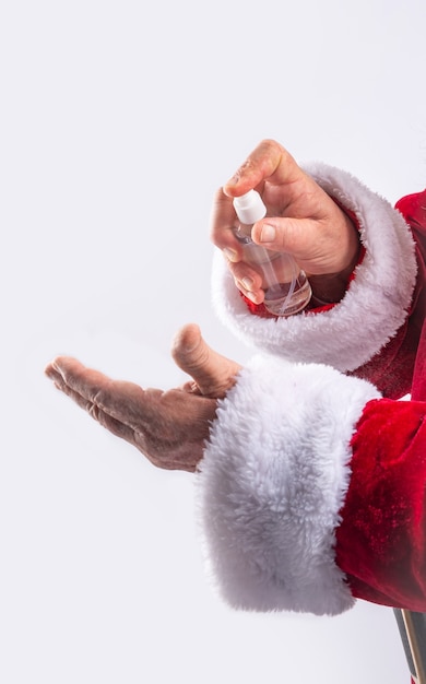 Père Noël nettoyant les mains avec du gel, empêchant le covid dans le mur blanc