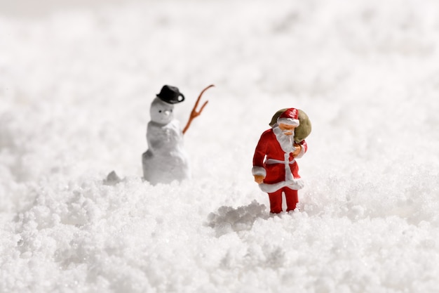 Père Noël ou Père Noël et un bonhomme de neige dans la neige d'hiver