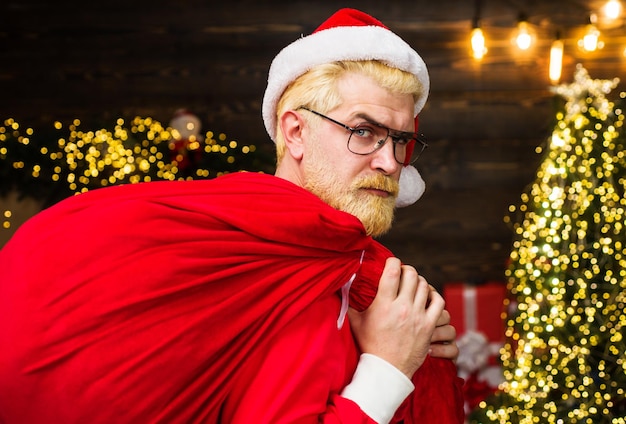 Père noël portant un sac rouge avec des cadeaux livraison cadeaux de noël publicité du nouvel an