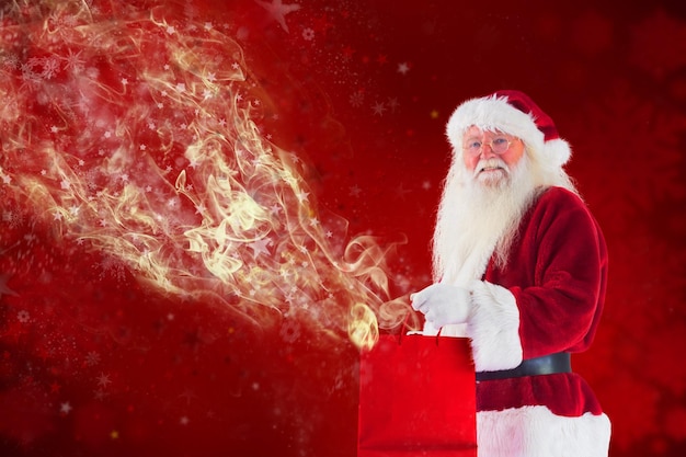 Le Père Noël porte un sac cadeau rouge contre la conception floue de flocon de neige