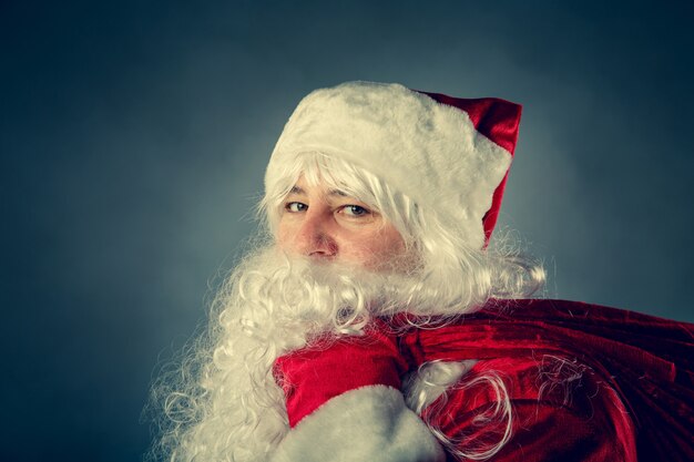 Le Père Noël porte un sac avec des cadeaux. Fantaisie de Noël.