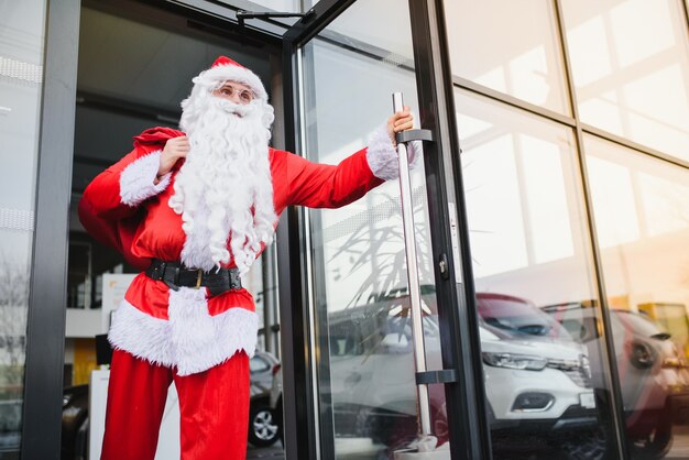 Père Noël près d'une nouvelle voiture chez un concessionnaire automobile.