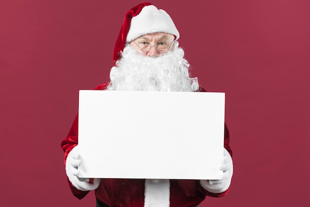 Photo père noël tenant du papier blanc dans les mains