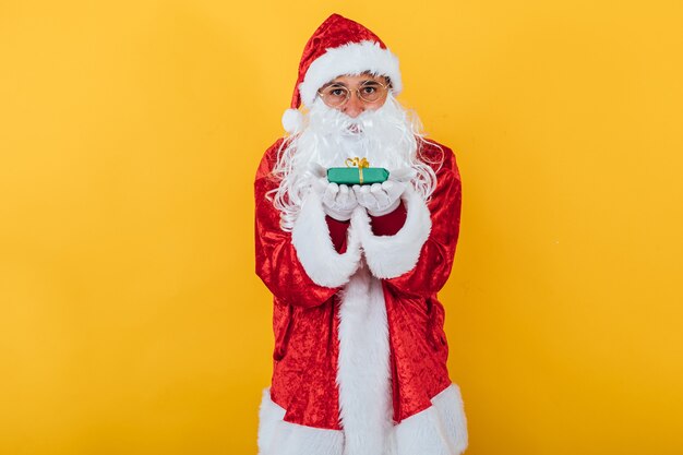 Le Père Noël tient un cadeau sur jaune