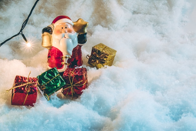 Le Père Noël tient la cloche et le cadeau, l'ampoule dans la nuit silencieuse, en joyeux Noël