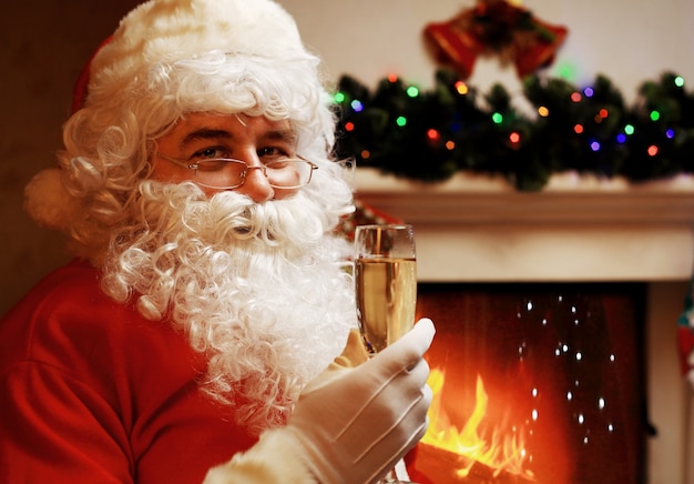 Père Noël avec un verre de champagne au vin mousseux près d'un arbre de Noël