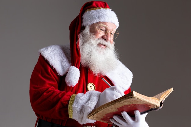 Père Noël avec un vieux livre de couverture rouge. Notez les noms des cadeaux pour Noël. Noël approche