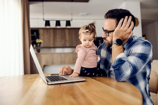 Un père et ouvrier surmené essayant de terminer le rapport pendant que sa fille le dérange