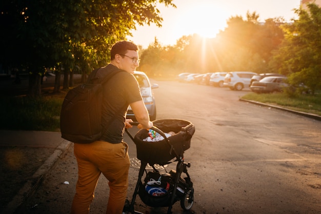 Père papa avec poussette landau nouveau-né à l&#39;extérieur pendant le coucher du soleil