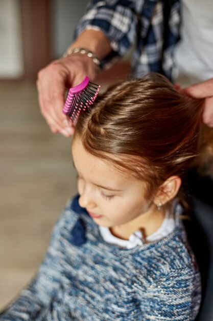 Père peignant, brossant les cheveux de sa fille à la maison