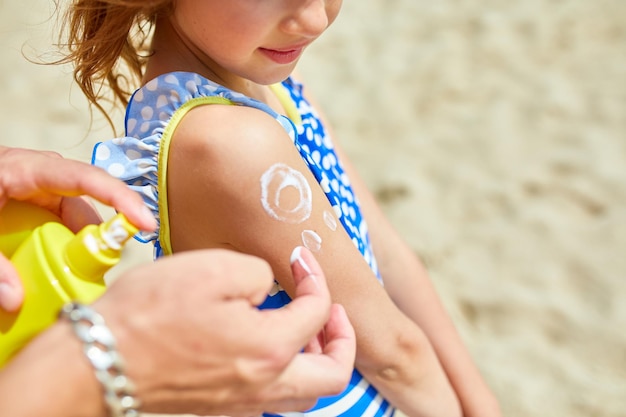 Père peignant par la crème solaire sur l'épaule en forme de soleil