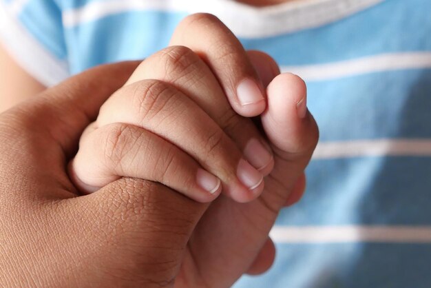 Photo père et petit fils se tenant par la main de près
