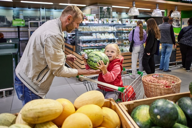 Le père et la petite fille choisissent la pastèque dans le supermarché