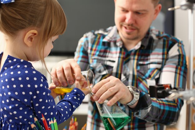 père et petite fille jouant avec des liquides colorés