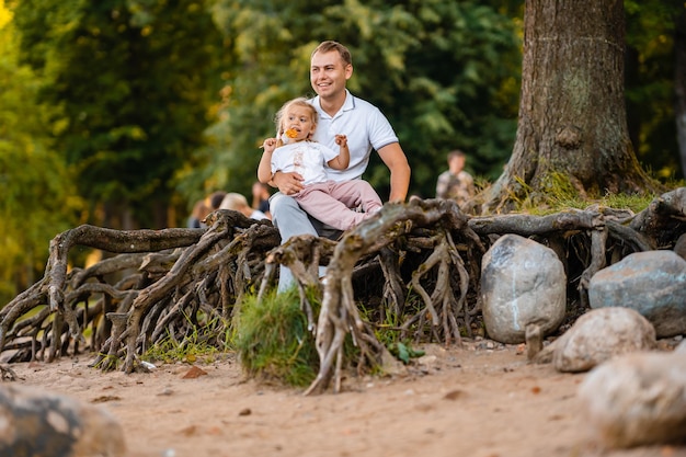 Père et petite fille mignonne ensemble en été dans la nature une petite fille mange une sucette