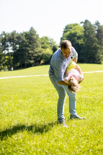 Père avec une petite fille mignonne s'amusant sur l'herbe du parc