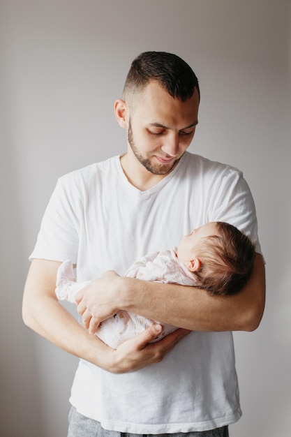 Un père porte sa petite fille sur un fond blanc.