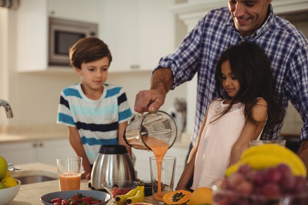 Photo père prépare un smoothie avec ses enfants dans la cuisine