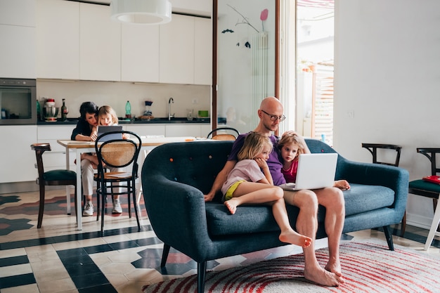 Père regardant un film en streaming sur ordinateur avec deux filles